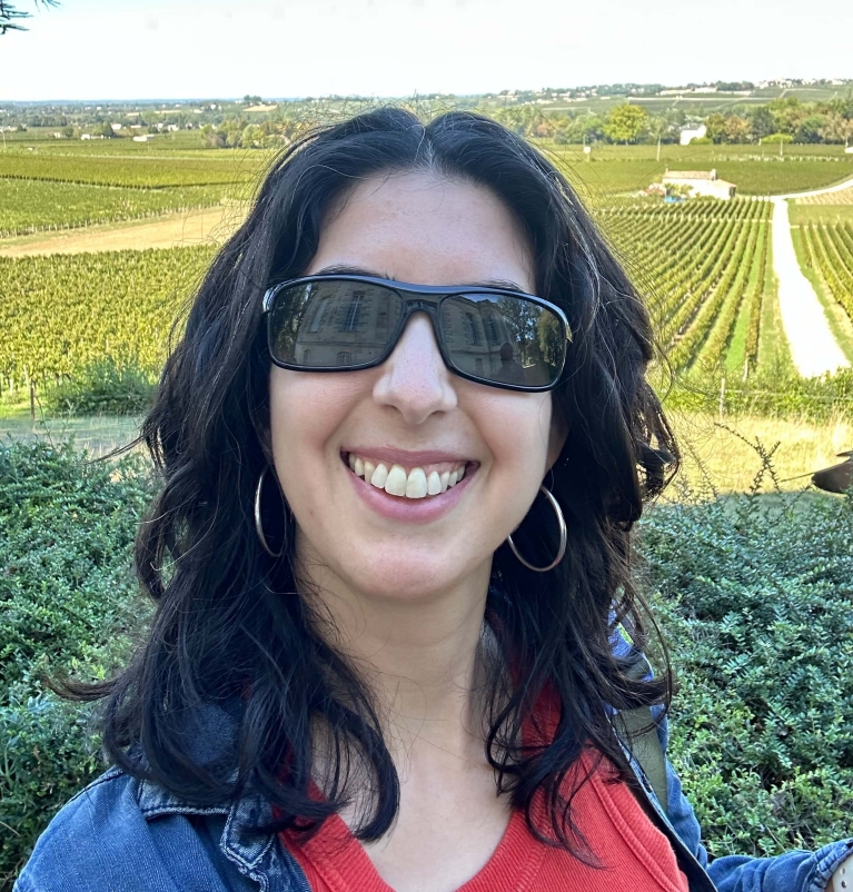 A selfie of a woman in sunglasses with vineyards in the background