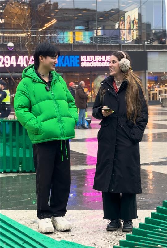 Two people speak in a busy shopping centre