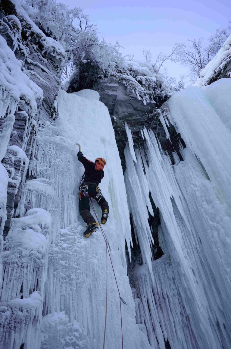 An ice climber scales a wall of ice in Abisko, Sweden