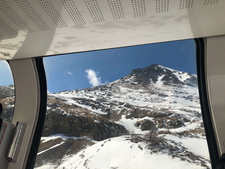 The view of mountains outside the window of a panoramic car of the Bernina Express