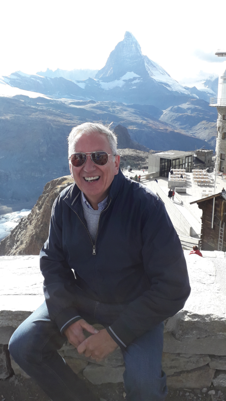 A man sits and smiles with the Matterhorn in the background