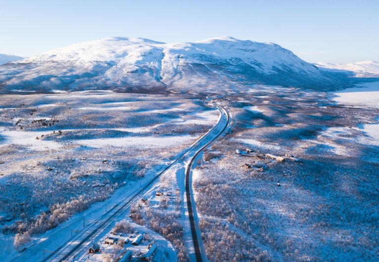 An aerial view of Abisko, Sweden, with snow-covered ground and mountains in the distance