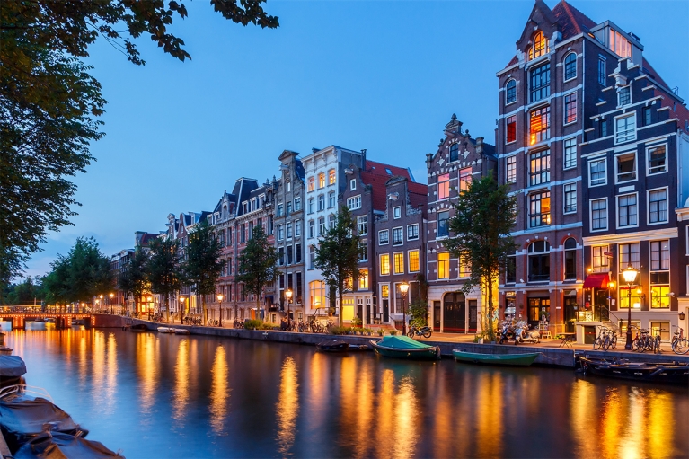 An Amsterdam canal at night, illuminated by streetlights