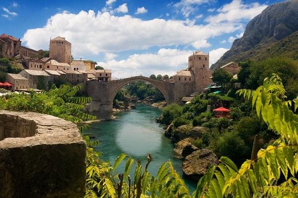 Old bridge in Mostar, surrounded by lush hillsides