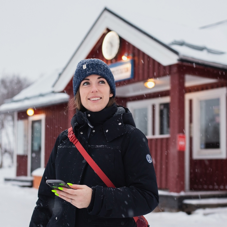 Rachel Schnalzer stands outside of a snow-covered train station